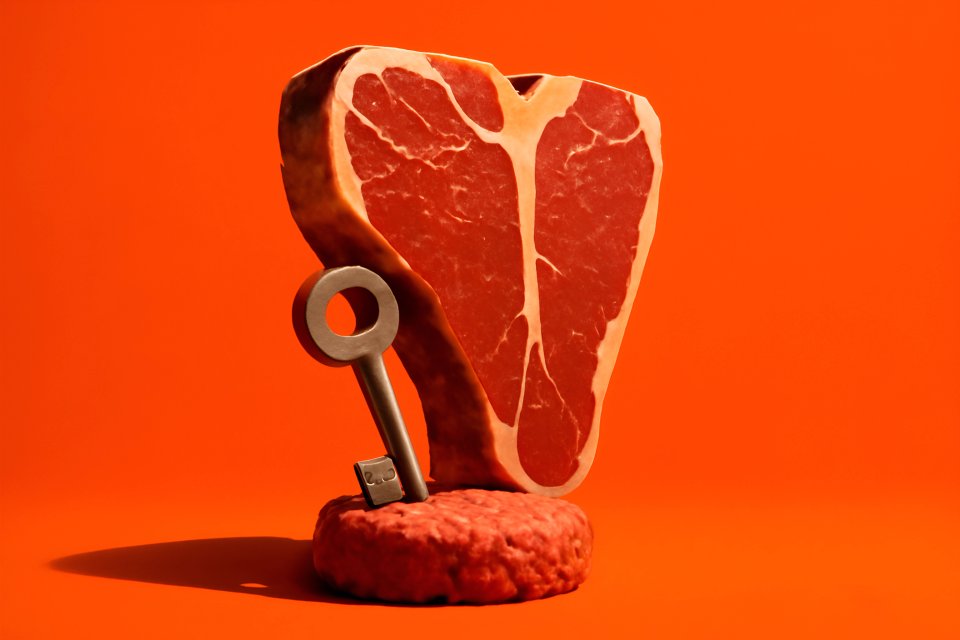 Steak with key on orange background